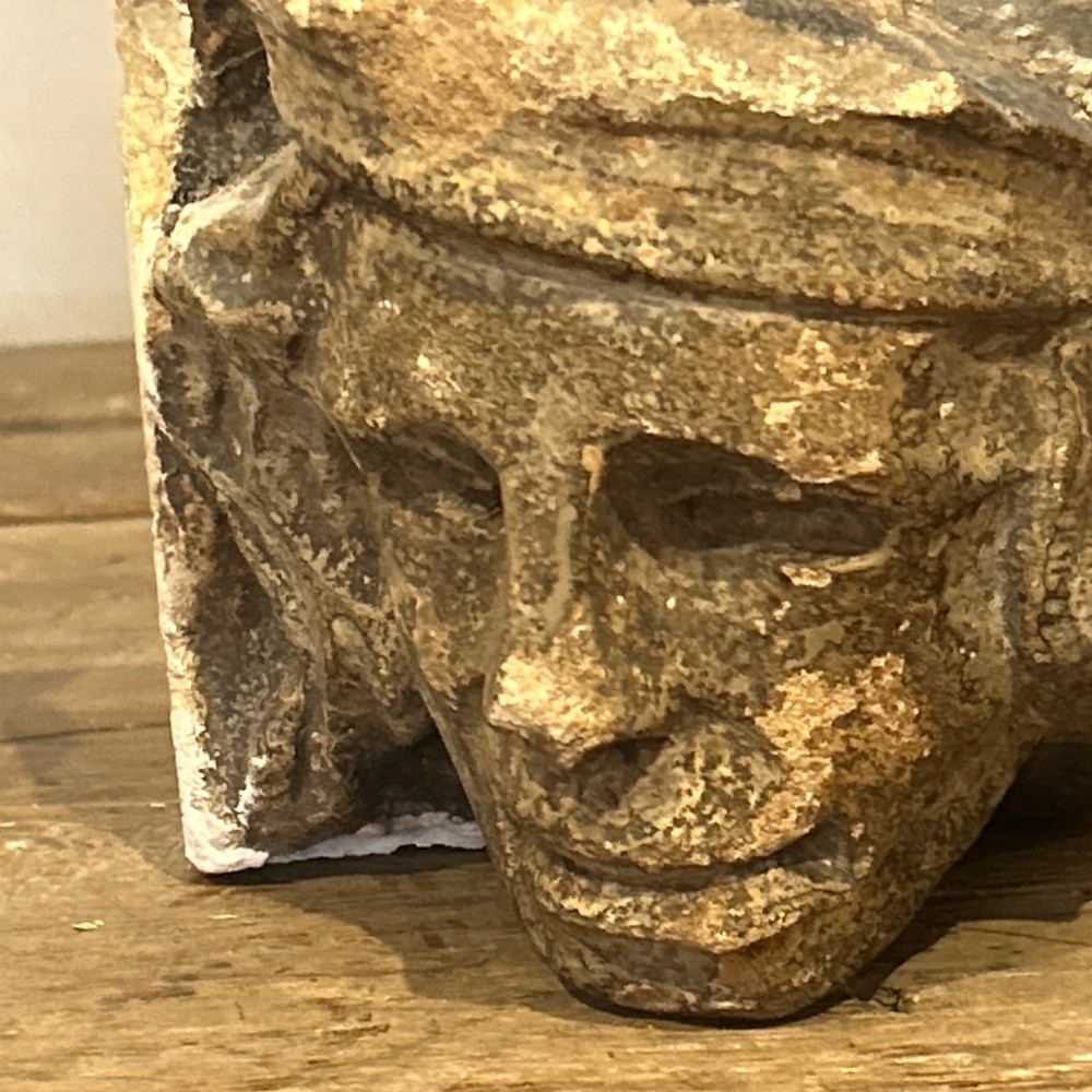 A pair of 15th-century carved limestone corbels depicting human heads with weathered facial features and period headwear. View VI