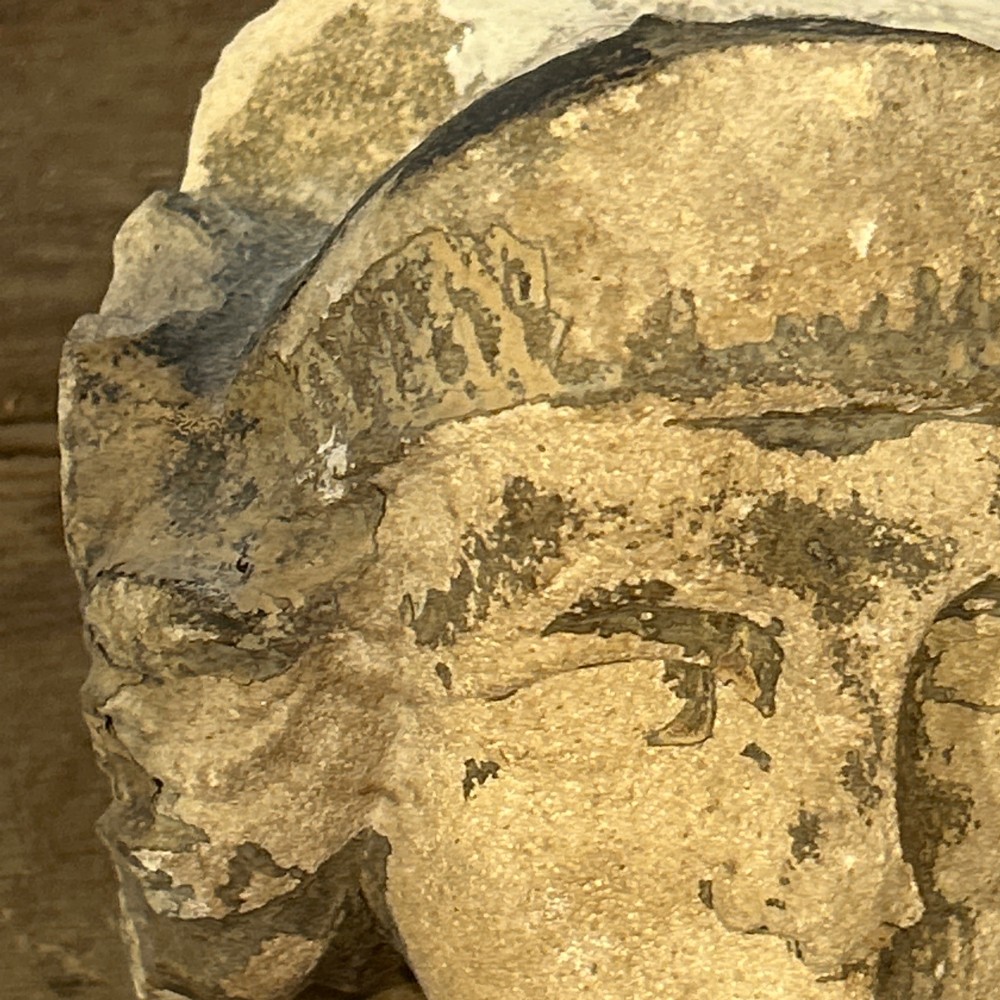 A pair of 15th-century carved limestone corbels depicting human heads with weathered facial features and period headwear. View VII