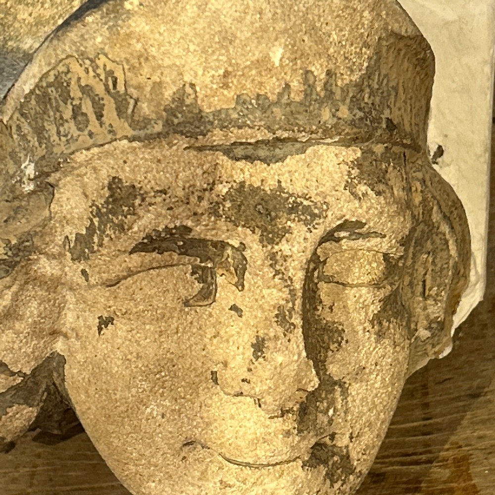 A pair of 15th-century carved limestone corbels depicting human heads with weathered facial features and period headwear. View VIII