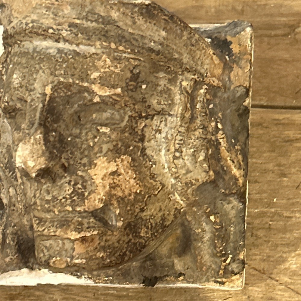 A pair of 15th-century carved limestone corbels depicting human heads with weathered facial features and period headwear. View IX