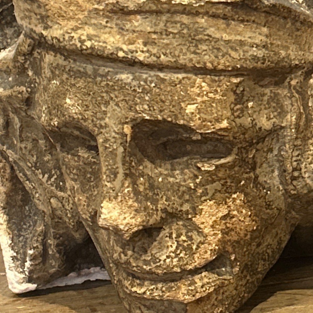 A pair of 15th-century carved limestone corbels depicting human heads with weathered facial features and period headwear. View XI