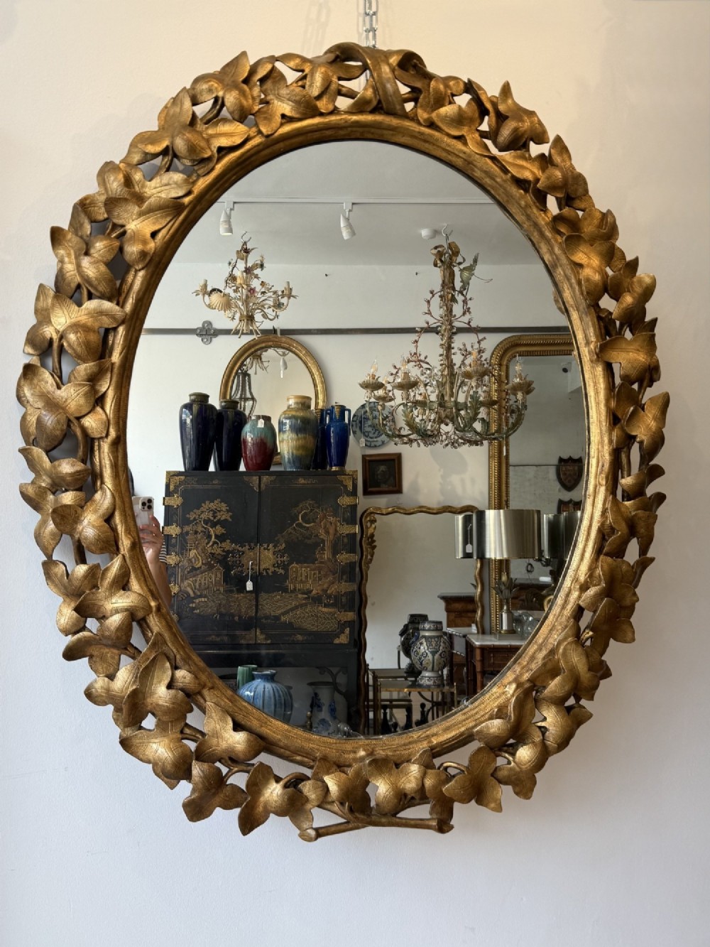 A large 19th-century oval wall mirror featuring a carved giltwood frame decorated with sculptural overlapping leaf motifs. View III