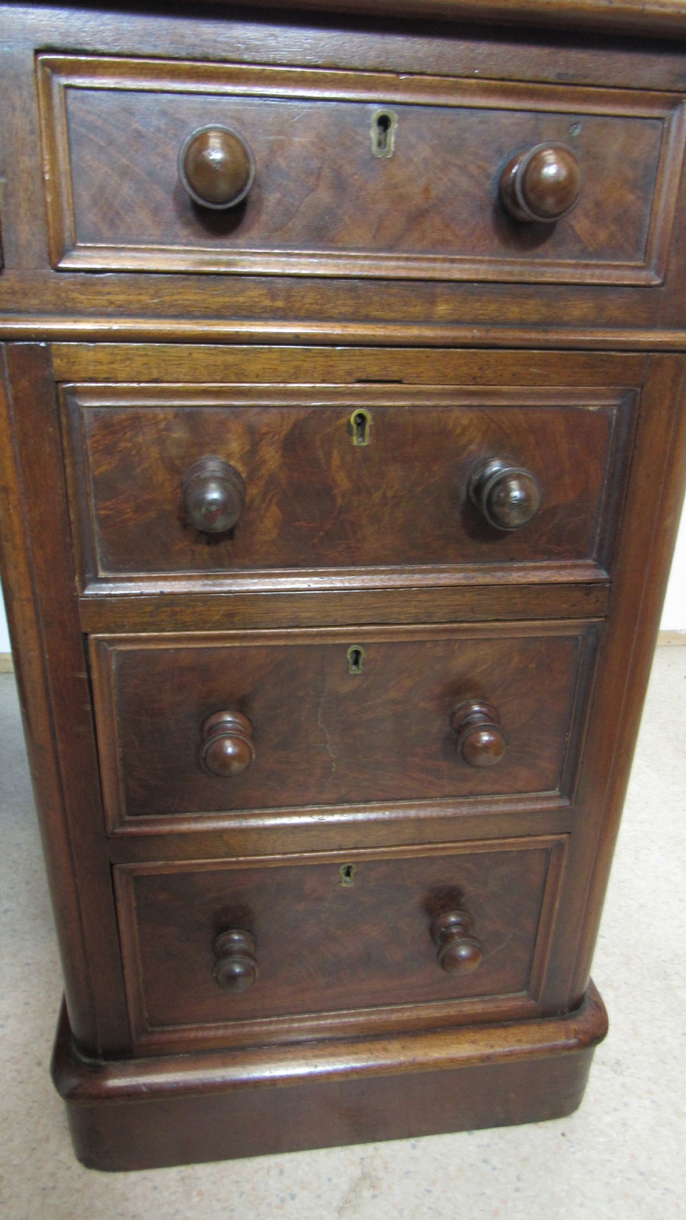 An antique mahogany pedestal desk featuring a red leather writing surface with gold tooling and nine drawers fitted with turned wooden handles. View XVI
