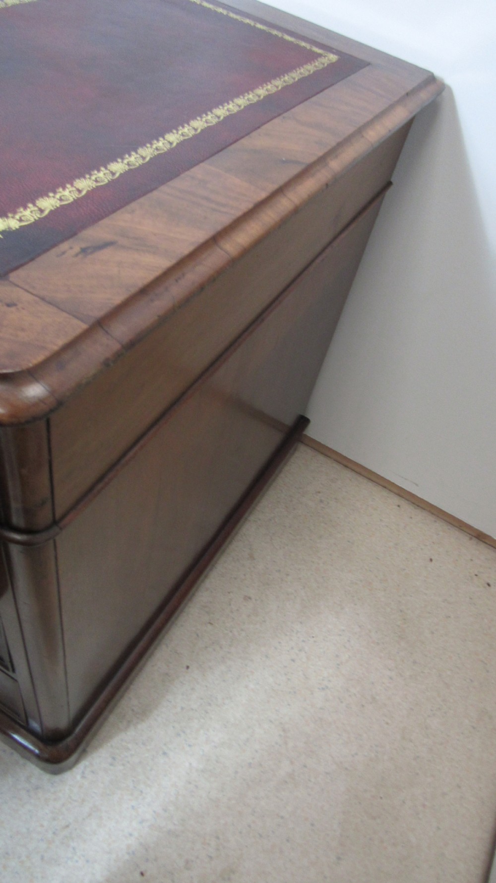 An antique mahogany pedestal desk featuring a red leather writing surface with gold tooling and nine drawers fitted with turned wooden handles. View XXII