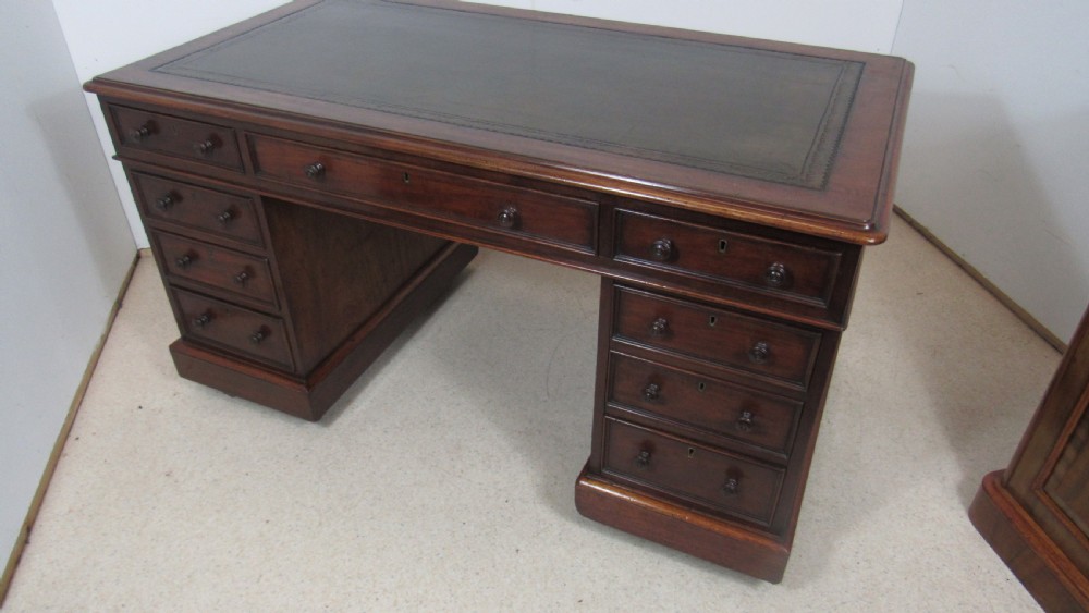A dark mahogany pedestal desk featuring an inset leather writing surface, multiple drawers fitted with turned wooden knobs, and a central kneehole. View XIII