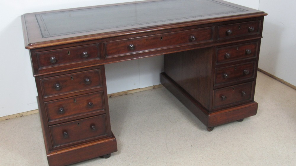 A dark mahogany pedestal desk featuring an inset leather writing surface, multiple drawers fitted with turned wooden knobs, and a central kneehole. View XIV