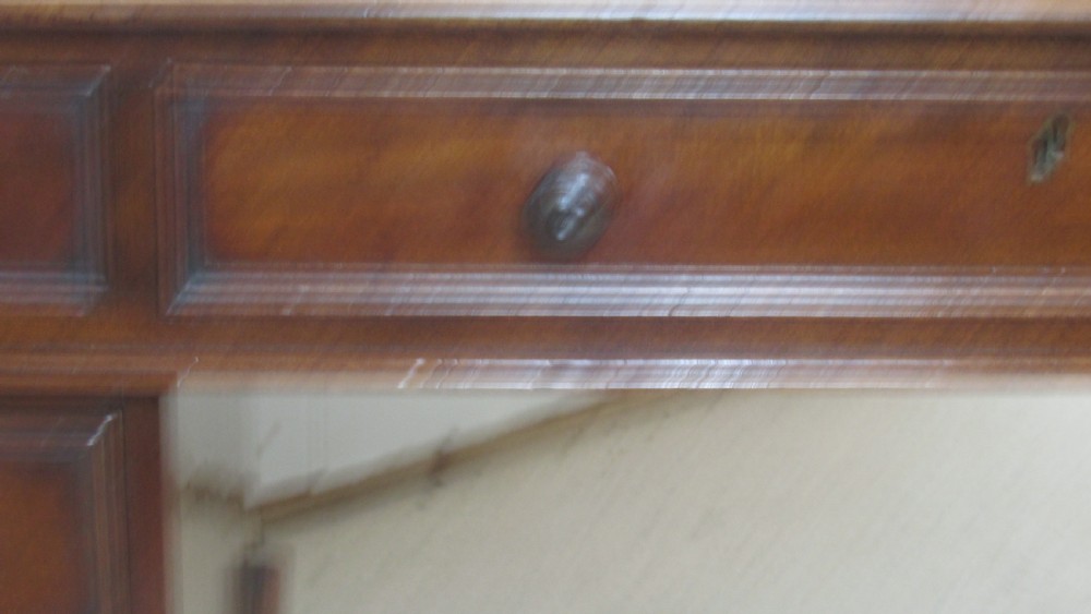 A dark mahogany pedestal desk featuring an inset leather writing surface, multiple drawers fitted with turned wooden knobs, and a central kneehole. View XVII