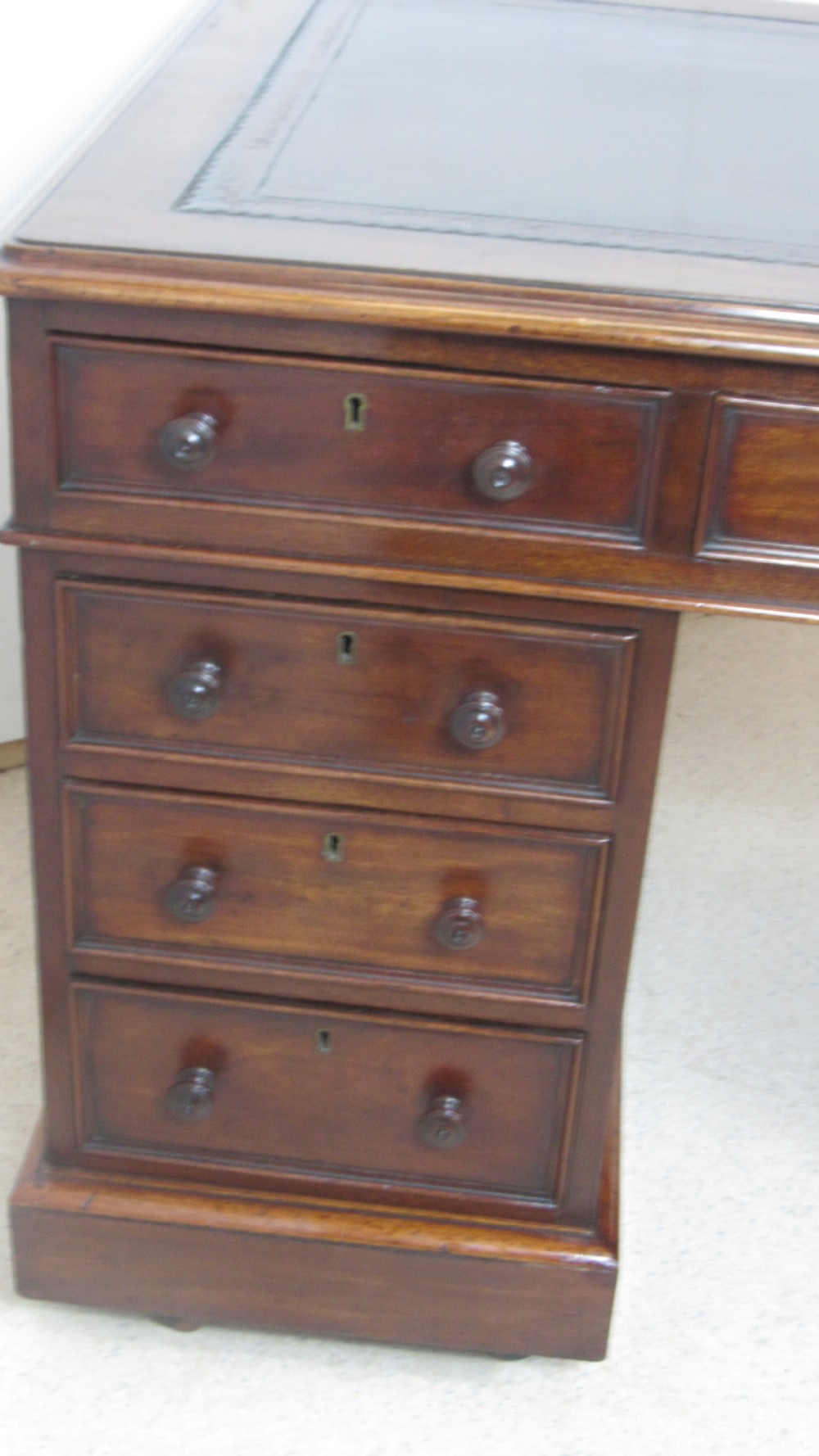 A dark mahogany pedestal desk featuring an inset leather writing surface, multiple drawers fitted with turned wooden knobs, and a central kneehole. View XVIII