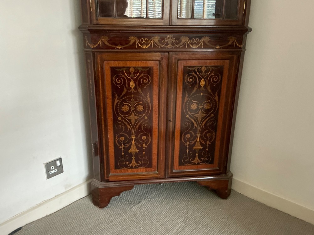An Edwardian mahogany corner cabinet featuring a broken pediment cresting, astragal glazed upper doors, and detailed floral marquetry inlays on the lower doors. View VII