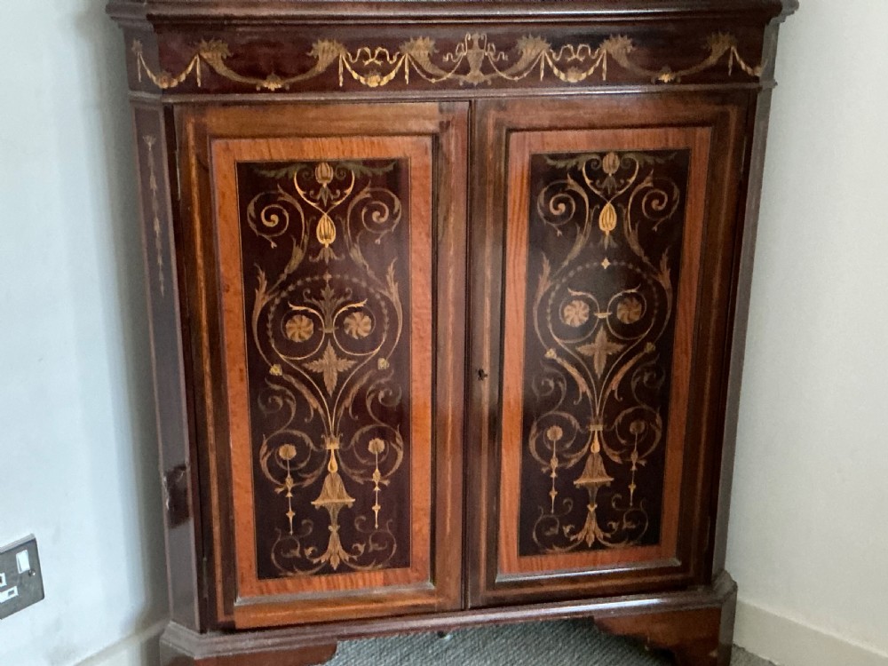 An Edwardian mahogany corner cabinet featuring a broken pediment cresting, astragal glazed upper doors, and detailed floral marquetry inlays on the lower doors. View VIII