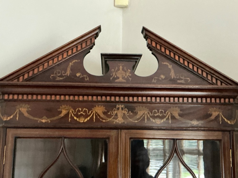 An Edwardian mahogany corner cabinet featuring a broken pediment cresting, astragal glazed upper doors, and detailed floral marquetry inlays on the lower doors. View X