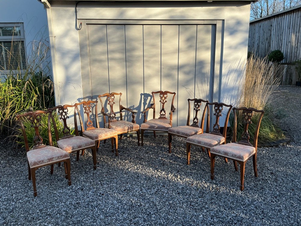 A set of eight mahogany Chippendale style dining chairs featuring elaborate pierced back splats and patterned upholstered seats.