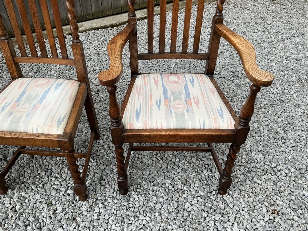 A set of six warm brown oak dining chairs, comprising two carver armchairs and four side chairs, featuring barley twist leg supports and vertical slatted backrests. View V