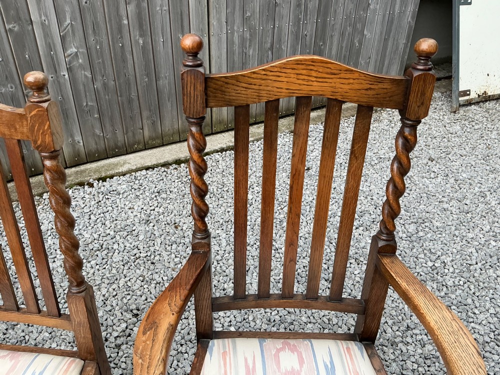 A set of six warm brown oak dining chairs, comprising two carver armchairs and four side chairs, featuring barley twist leg supports and vertical slatted backrests. View VI