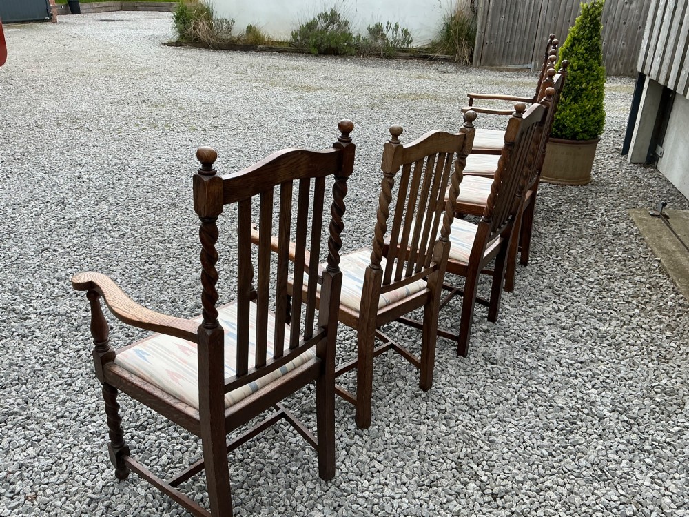 A set of six warm brown oak dining chairs, comprising two carver armchairs and four side chairs, featuring barley twist leg supports and vertical slatted backrests. View VII