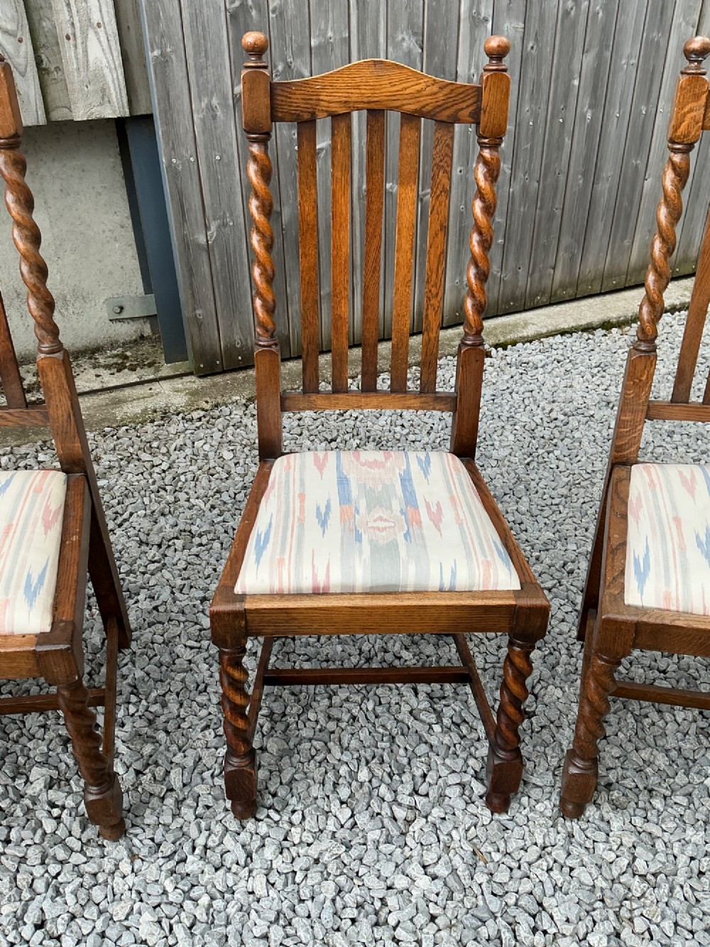 A set of six warm brown oak dining chairs, comprising two carver armchairs and four side chairs, featuring barley twist leg supports and vertical slatted backrests. View IX