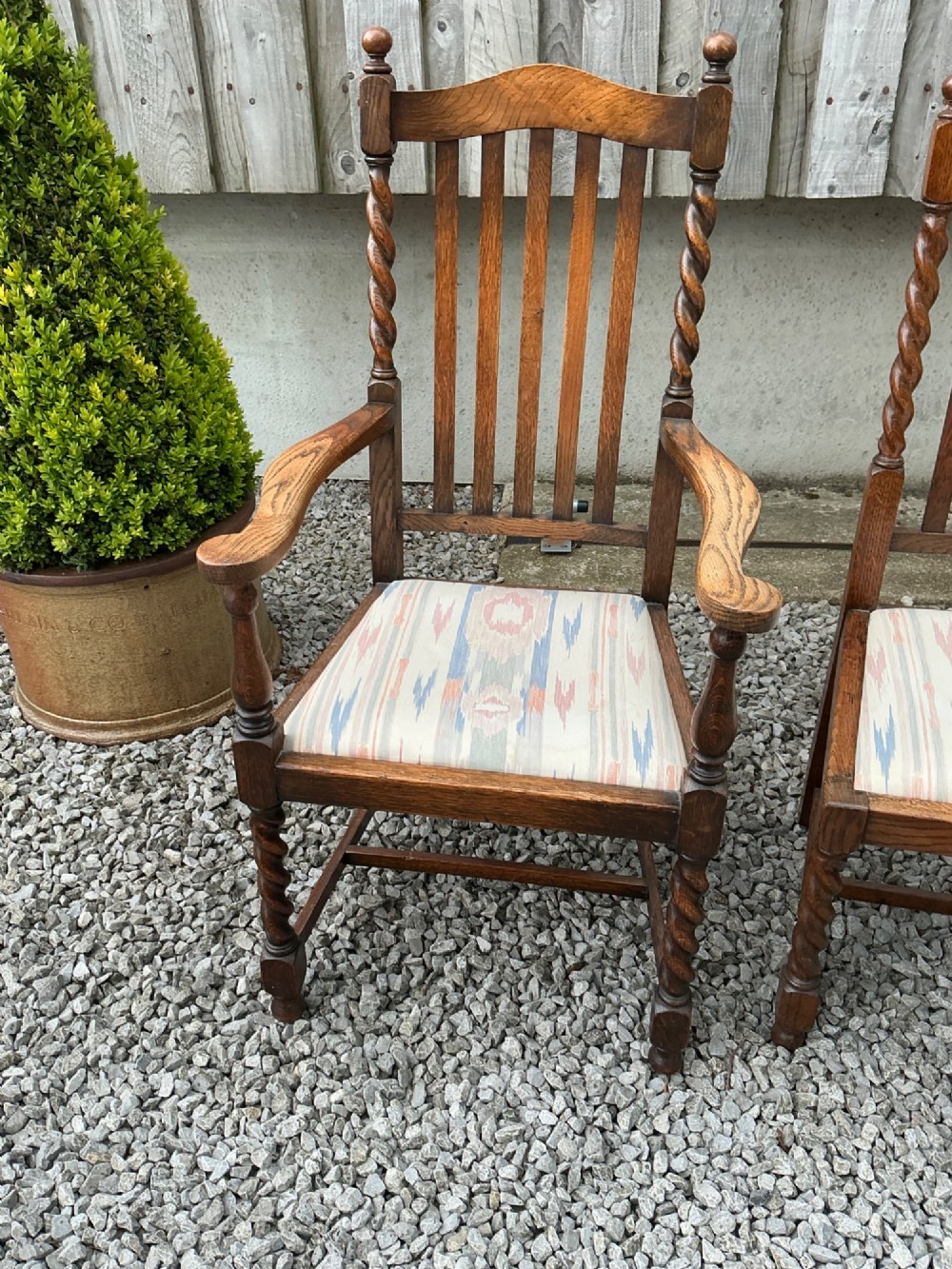 A set of six warm brown oak dining chairs, comprising two carver armchairs and four side chairs, featuring barley twist leg supports and vertical slatted backrests. View X
