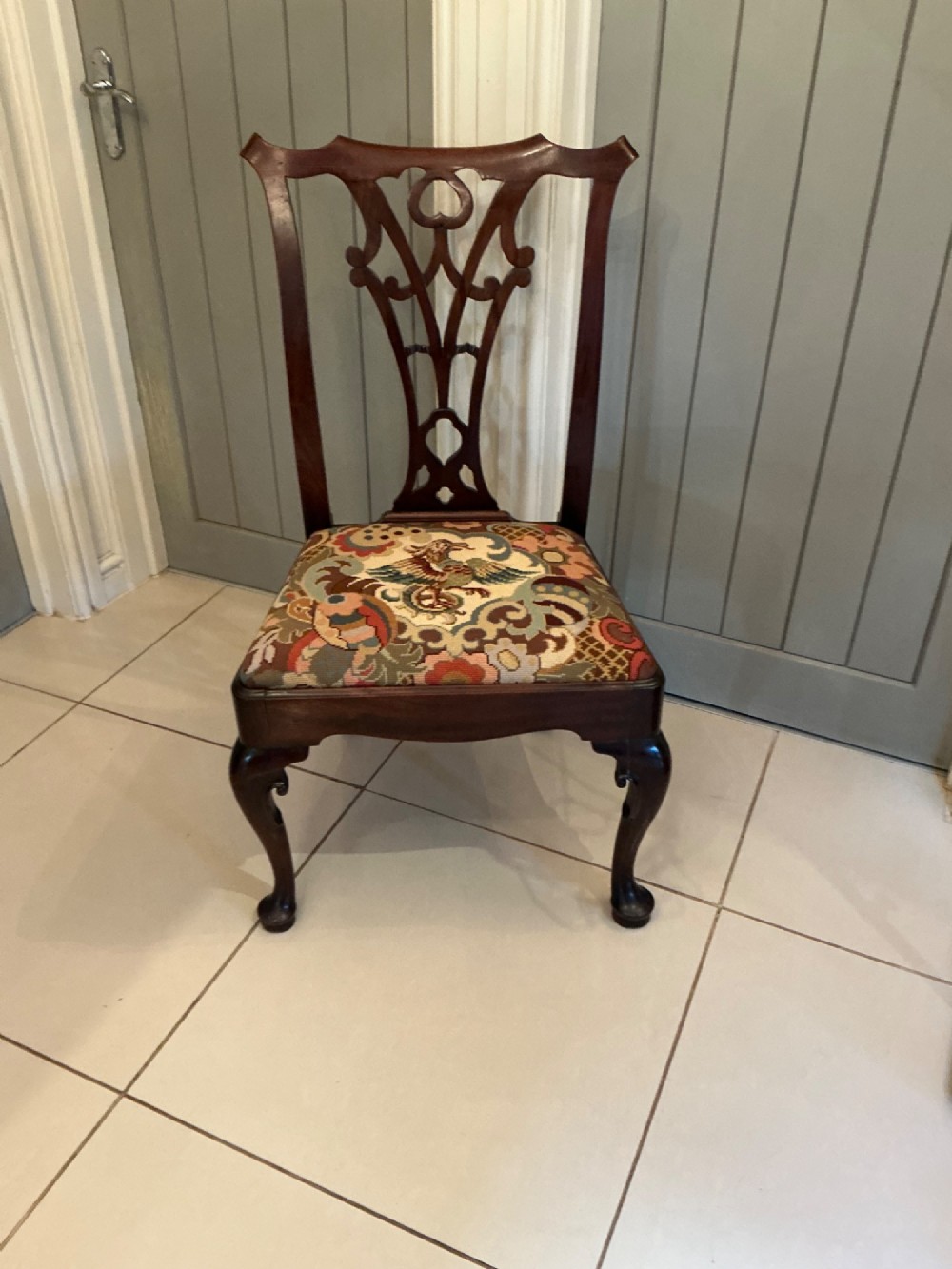 A Georgian mahogany side chair featuring a carved pierced splat back, cabriole front legs, and a needlepoint drop-in seat with a bird pattern.