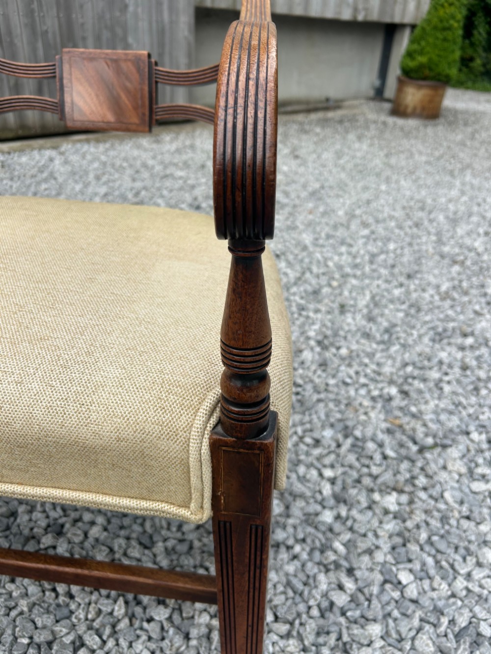 A set of eight Georgian mahogany dining chairs featuring reeded legs, carved bar backs, and beige upholstered seats, comprising six side chairs and two armchairs. View III