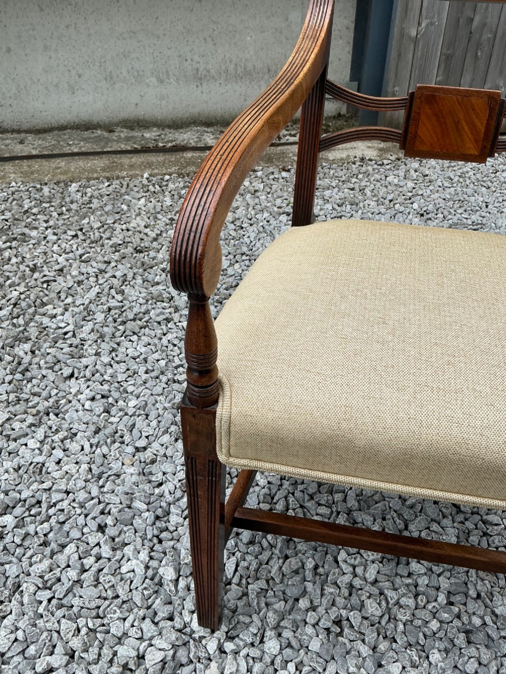 A set of eight Georgian mahogany dining chairs featuring reeded legs, carved bar backs, and beige upholstered seats, comprising six side chairs and two armchairs. View VI