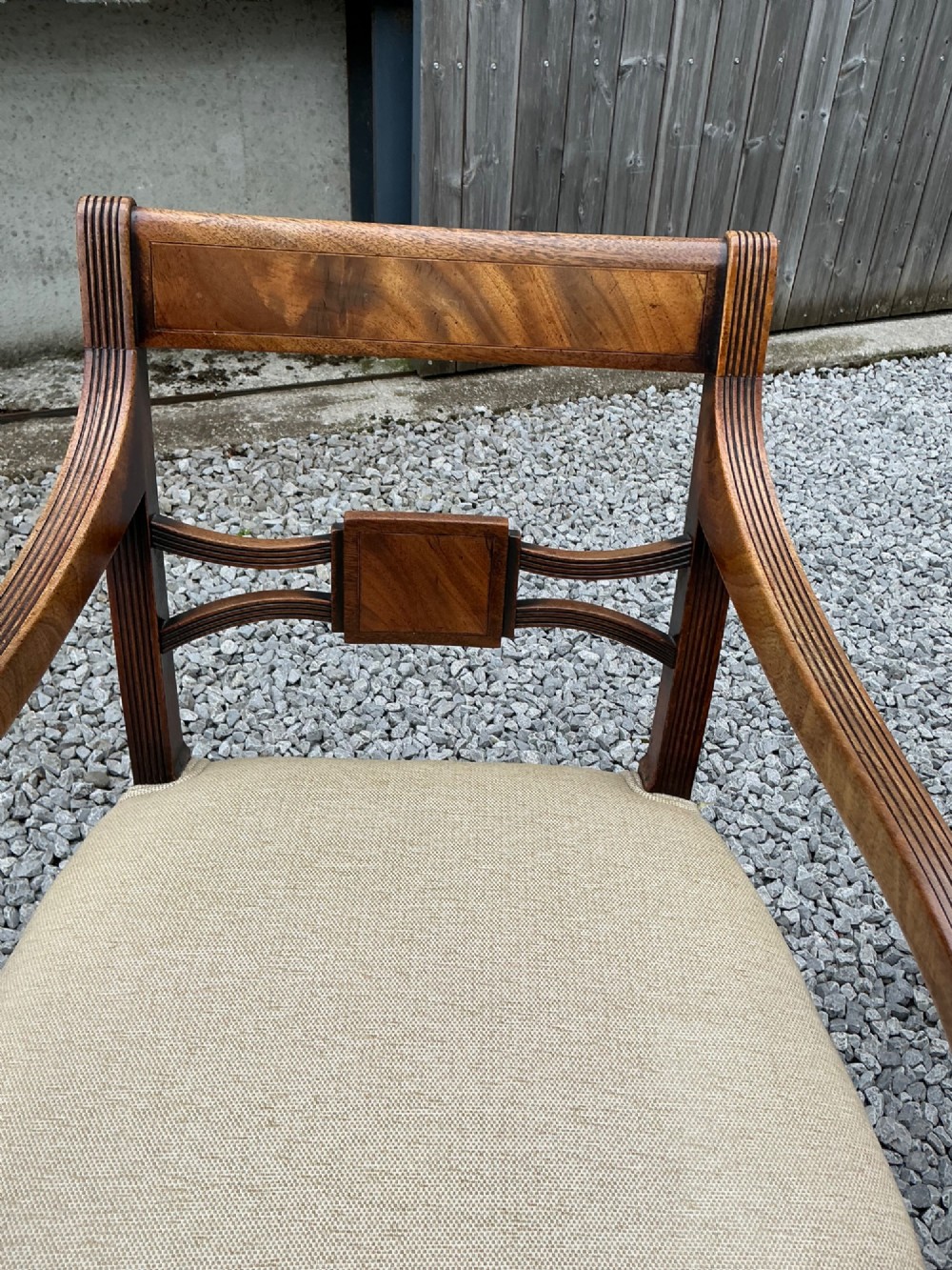 A set of eight Georgian mahogany dining chairs featuring reeded legs, carved bar backs, and beige upholstered seats, comprising six side chairs and two armchairs. View VII