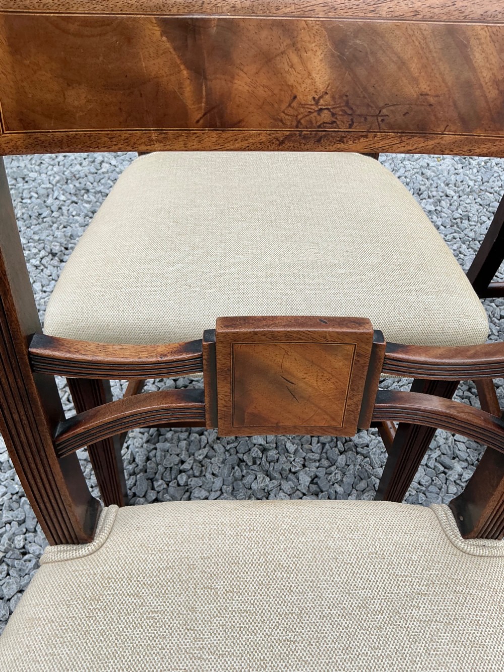 A set of eight Georgian mahogany dining chairs featuring reeded legs, carved bar backs, and beige upholstered seats, comprising six side chairs and two armchairs. View IX