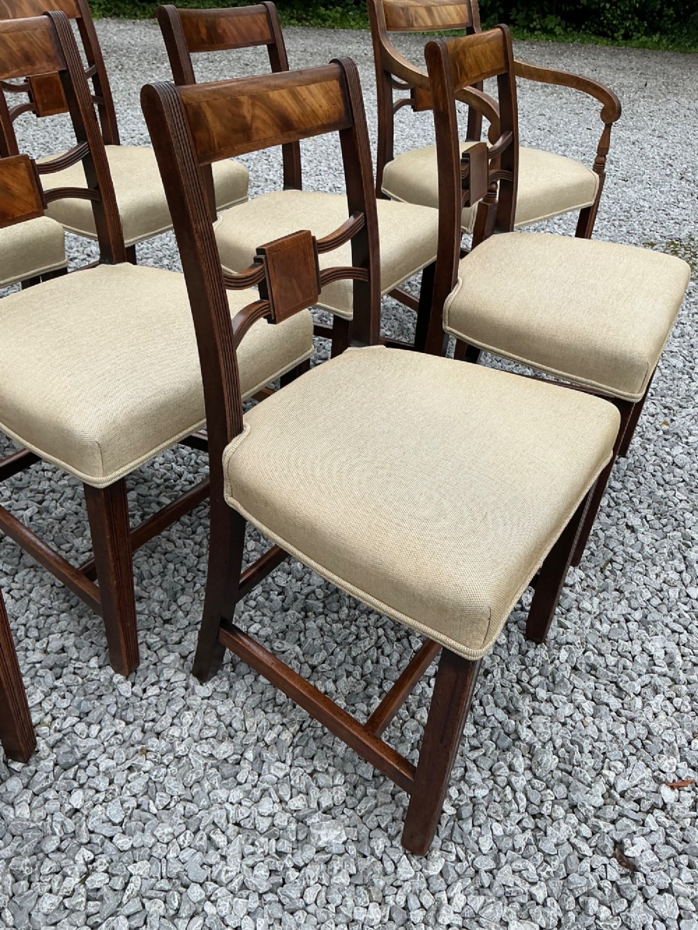A set of eight Georgian mahogany dining chairs featuring reeded legs, carved bar backs, and beige upholstered seats, comprising six side chairs and two armchairs. View XIII
