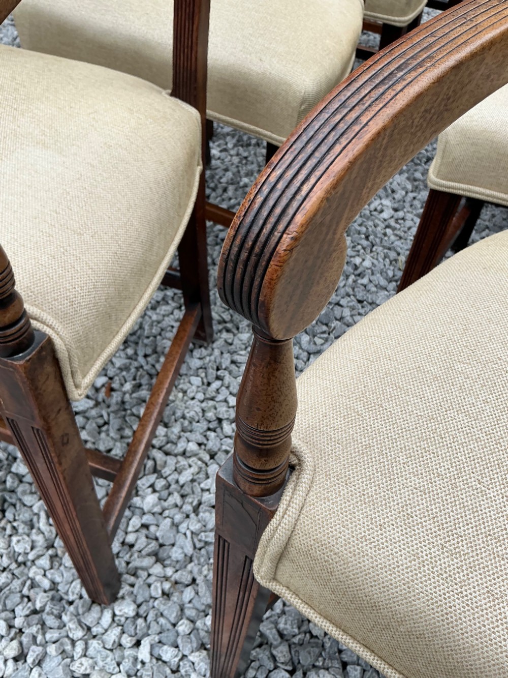 A set of eight Georgian mahogany dining chairs featuring reeded legs, carved bar backs, and beige upholstered seats, comprising six side chairs and two armchairs. View XIV
