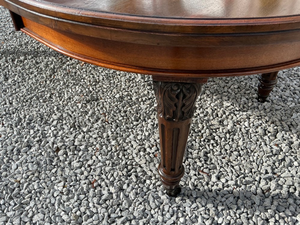 A large Victorian mahogany extending dining table with rounded ends, removable insert leaf, carved legs, and a rich polished finish. View II