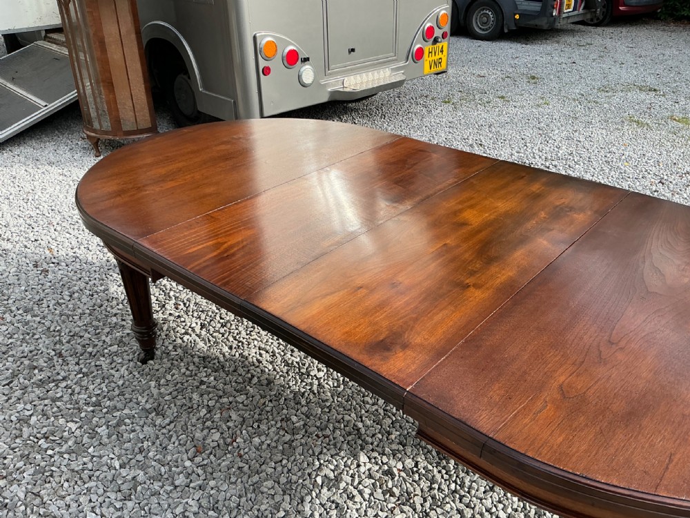 A large Victorian mahogany extending dining table with rounded ends, removable insert leaf, carved legs, and a rich polished finish. View III