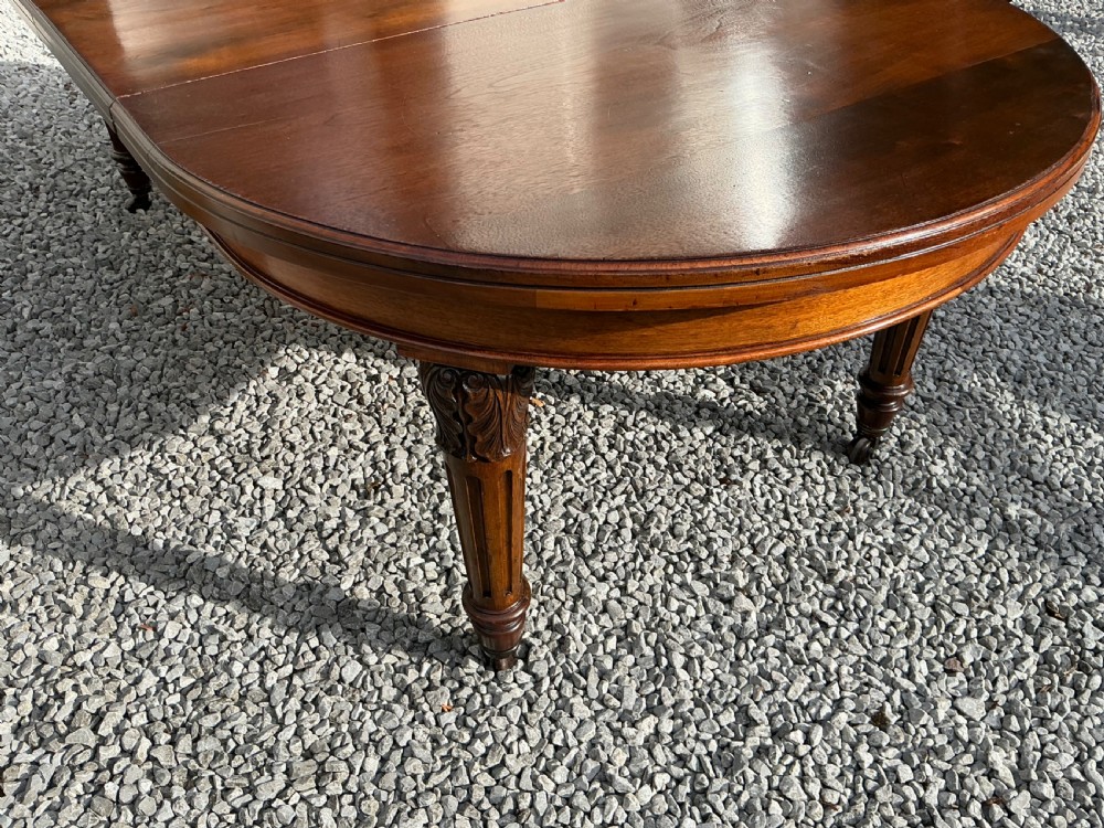 A large Victorian mahogany extending dining table with rounded ends, removable insert leaf, carved legs, and a rich polished finish. View IV