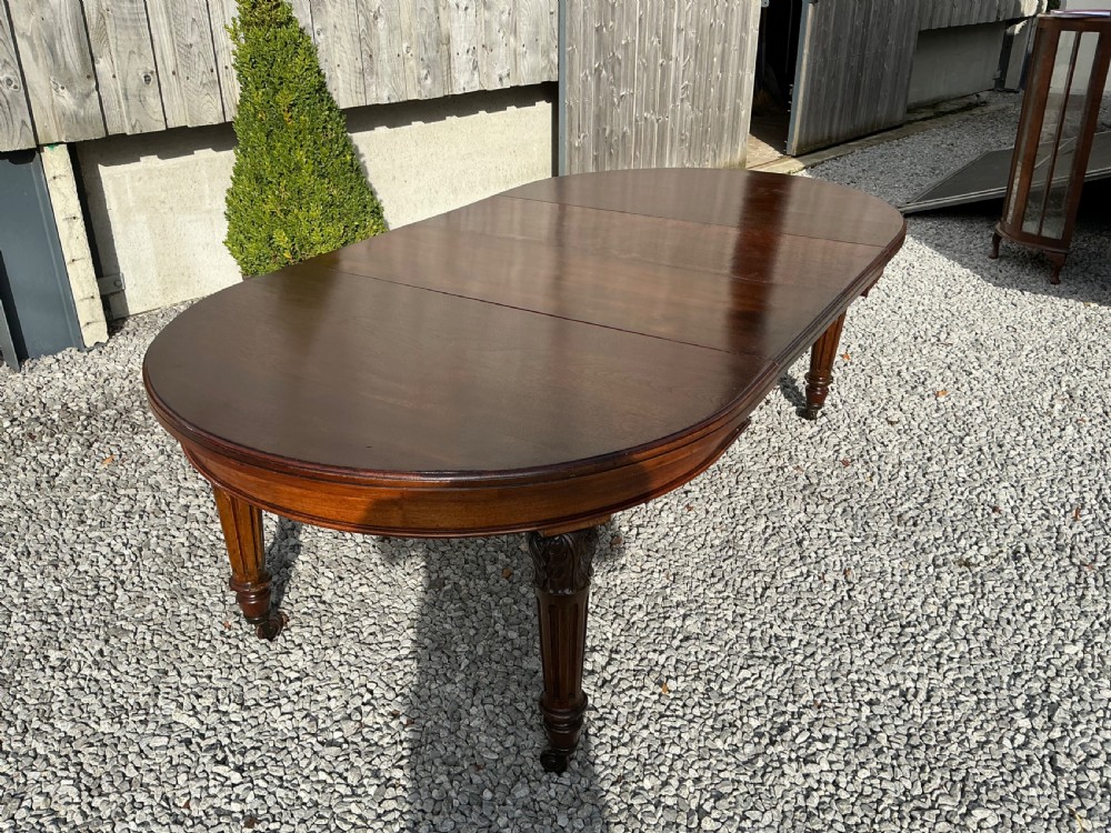 A large Victorian mahogany extending dining table with rounded ends, removable insert leaf, carved legs, and a rich polished finish. View V