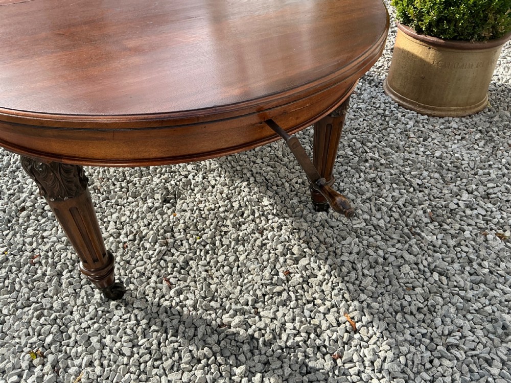A large Victorian mahogany extending dining table with rounded ends, removable insert leaf, carved legs, and a rich polished finish. View VI