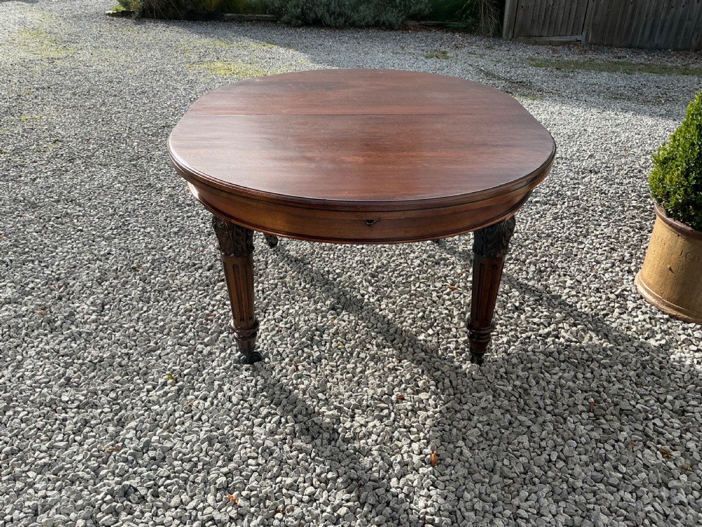 A large Victorian mahogany extending dining table with rounded ends, removable insert leaf, carved legs, and a rich polished finish. View VII
