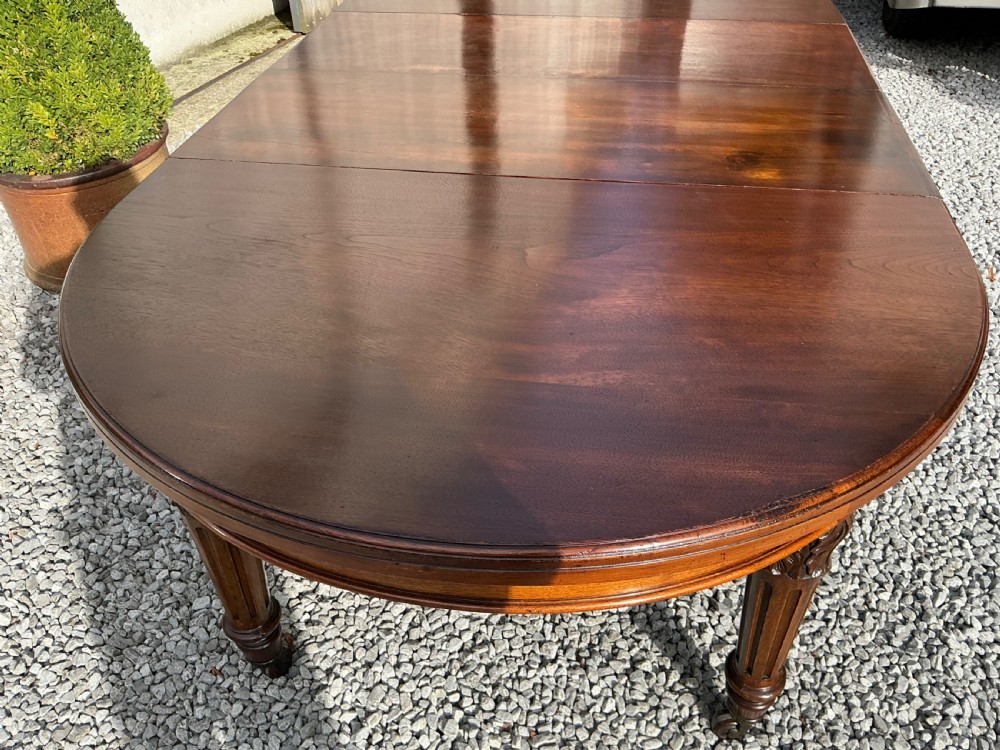 A large Victorian mahogany extending dining table with rounded ends, removable insert leaf, carved legs, and a rich polished finish. View VIII