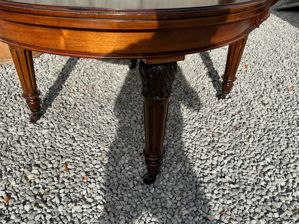 A large Victorian mahogany extending dining table with rounded ends, removable insert leaf, carved legs, and a rich polished finish. View IX