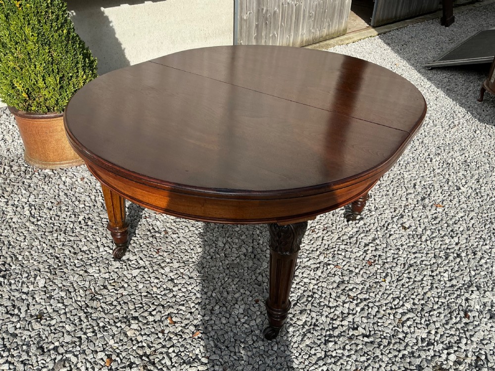 A large Victorian mahogany extending dining table with rounded ends, removable insert leaf, carved legs, and a rich polished finish. View X