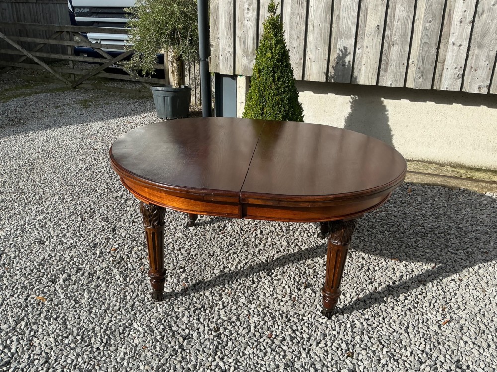 A large Victorian mahogany extending dining table with rounded ends, removable insert leaf, carved legs, and a rich polished finish. View XII