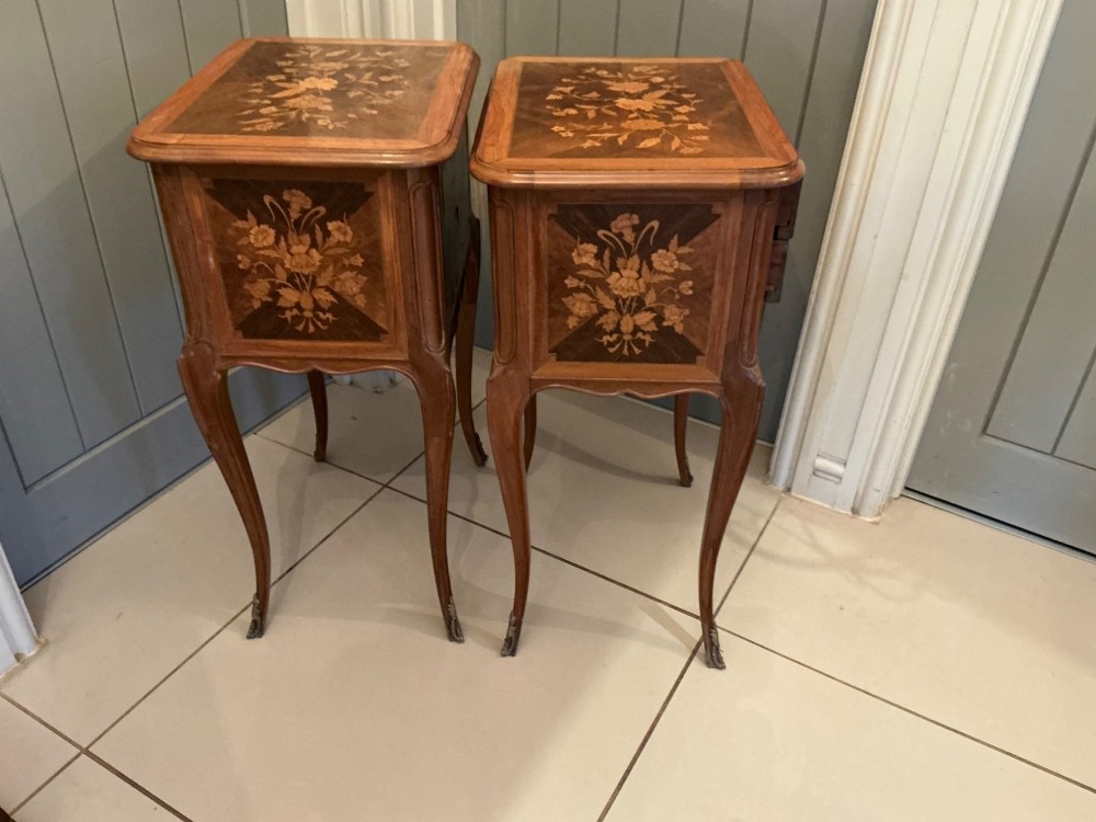 A pair of French Louis XV style wooden bedside tables decorated with intricate floral marquetry inlays and supported by cabriole legs with metal sabots. View V