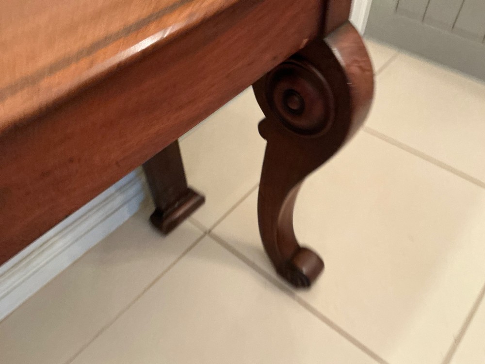 A William IV mahogany console table featuring curved scroll front legs, a low rear gallery, and a polished rectangular top. View IV