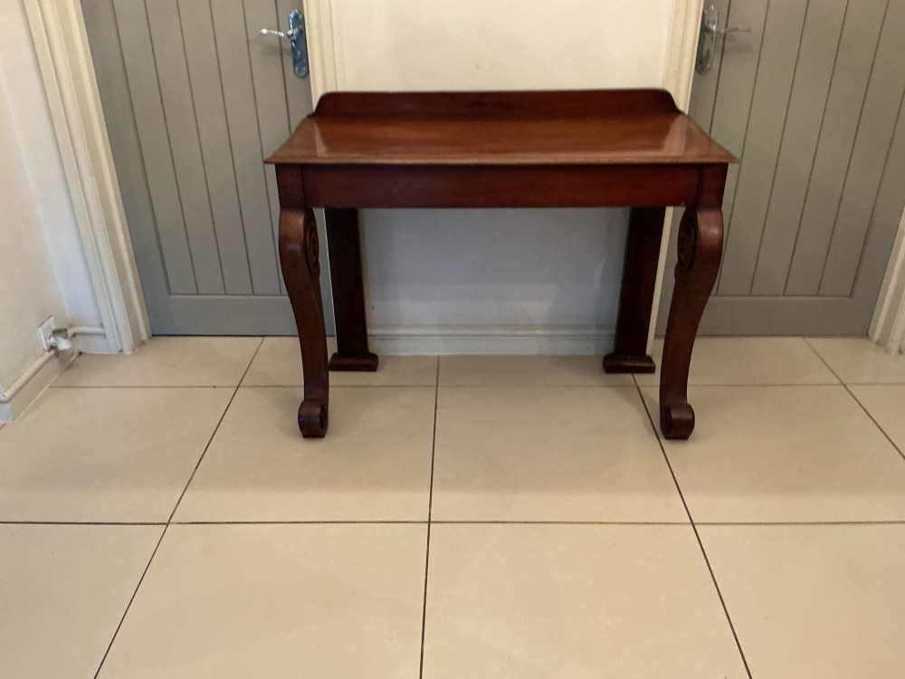 A William IV mahogany console table featuring curved scroll front legs, a low rear gallery, and a polished rectangular top. View IX