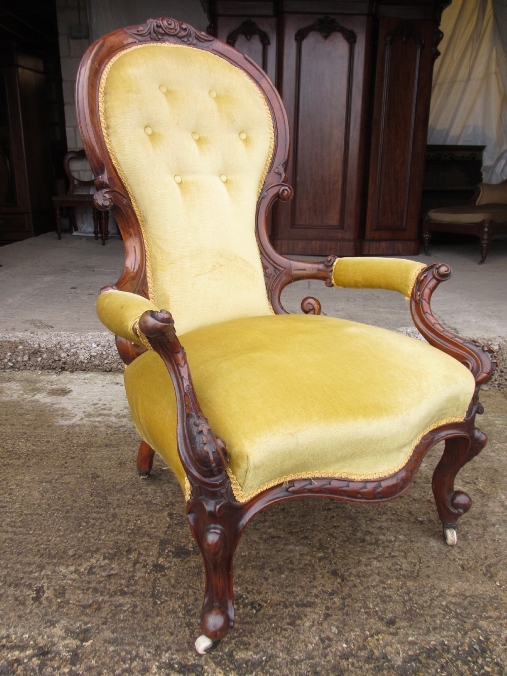 A Victorian walnut open armchair featuring a curved spoon back with button-tufted yellow velvet upholstery and carved cabriole legs. View II