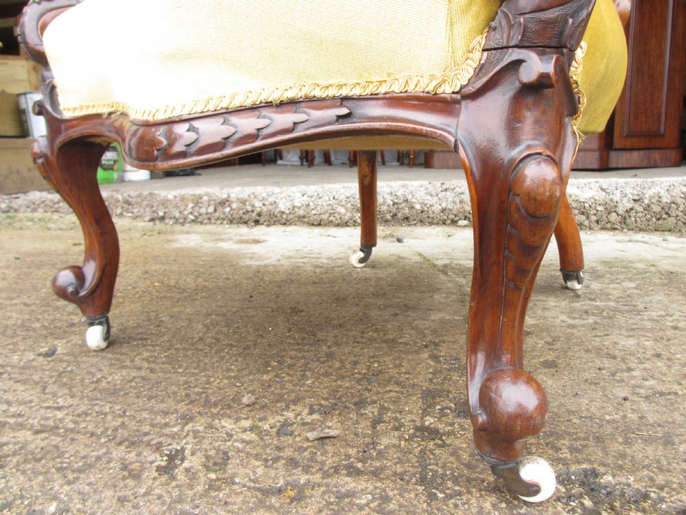 A Victorian walnut open armchair featuring a curved spoon back with button-tufted yellow velvet upholstery and carved cabriole legs. View V