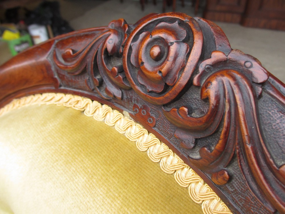 A Victorian walnut open armchair featuring a curved spoon back with button-tufted yellow velvet upholstery and carved cabriole legs. View VI