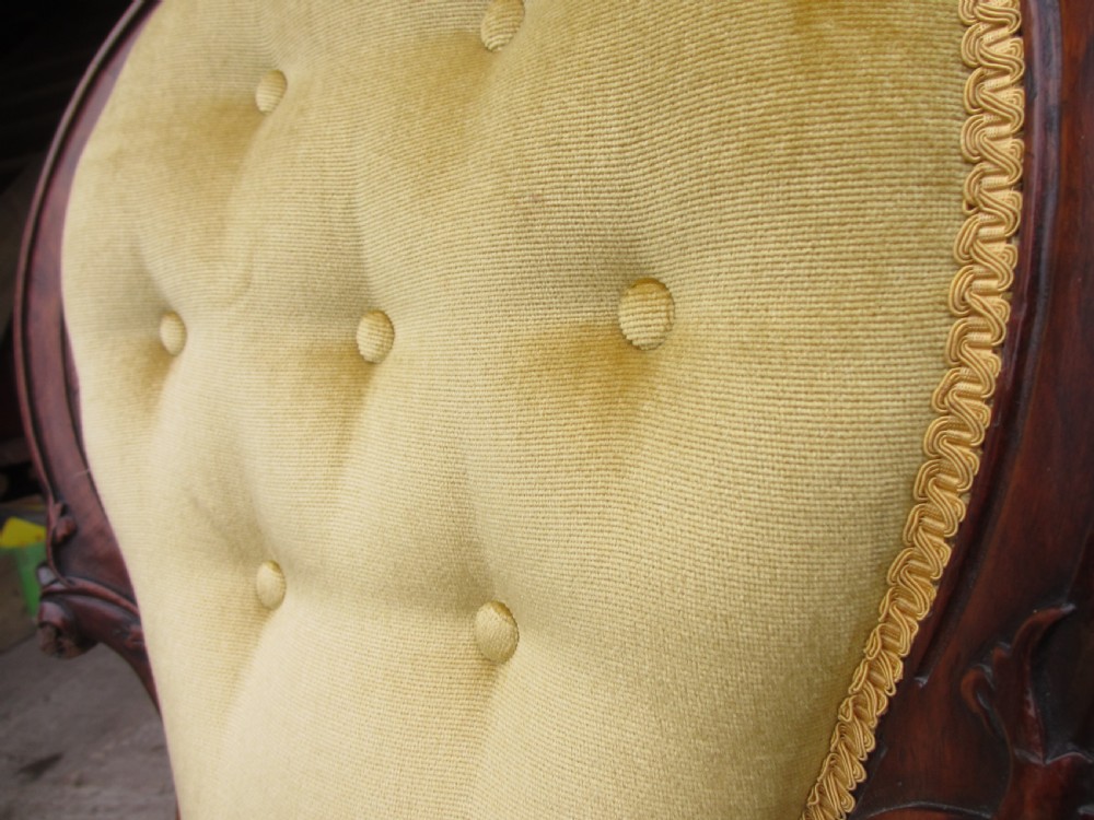 A Victorian walnut open armchair featuring a curved spoon back with button-tufted yellow velvet upholstery and carved cabriole legs. View VII