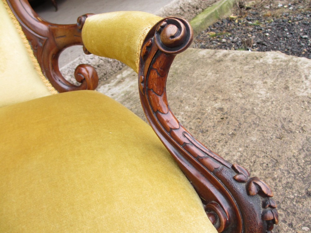A Victorian walnut open armchair featuring a curved spoon back with button-tufted yellow velvet upholstery and carved cabriole legs. View VIII
