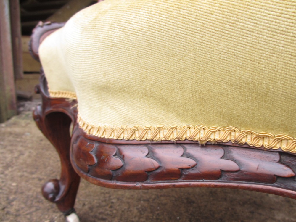 A Victorian walnut open armchair featuring a curved spoon back with button-tufted yellow velvet upholstery and carved cabriole legs. View IX