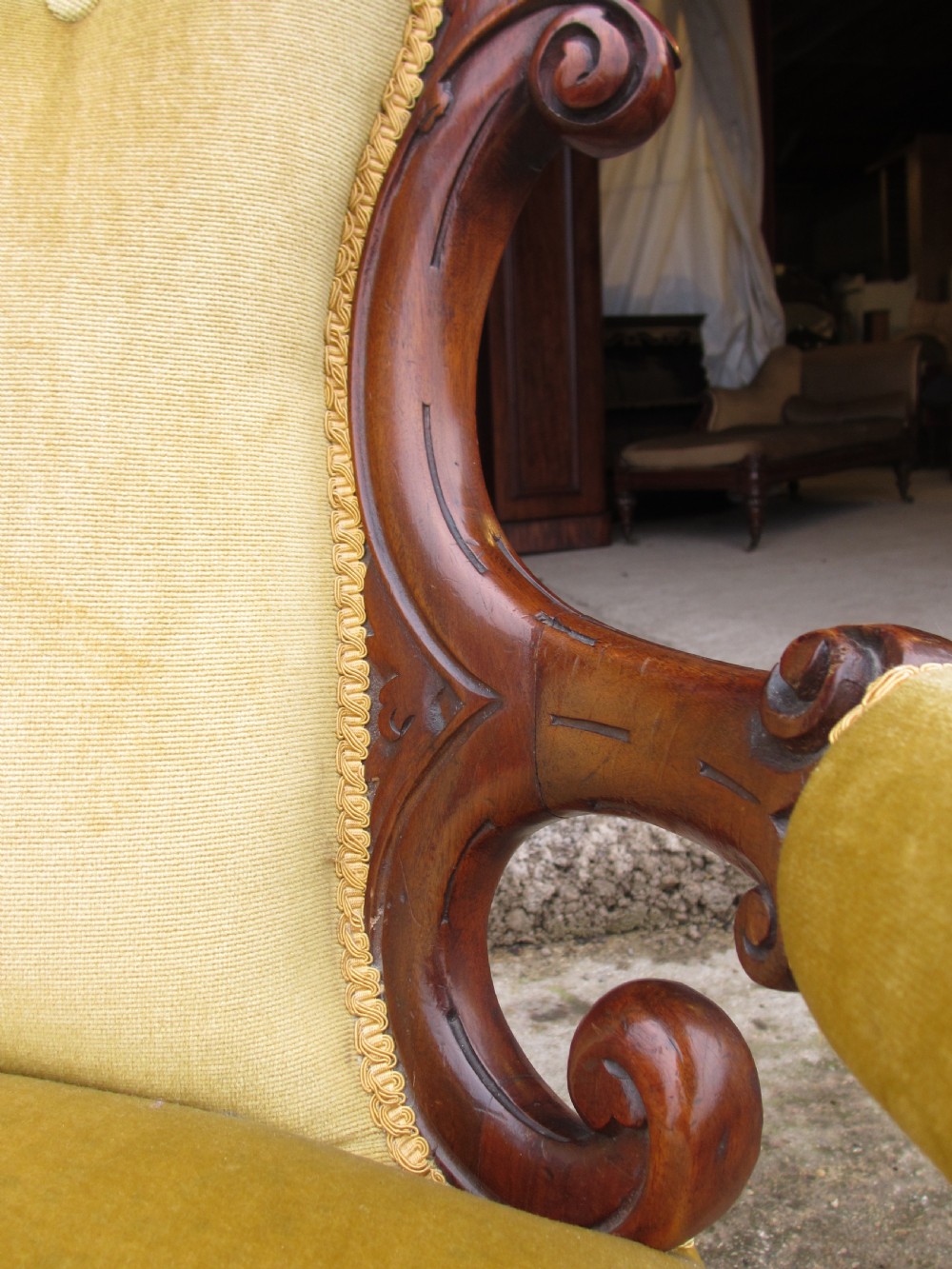 A Victorian walnut open armchair featuring a curved spoon back with button-tufted yellow velvet upholstery and carved cabriole legs. View XI