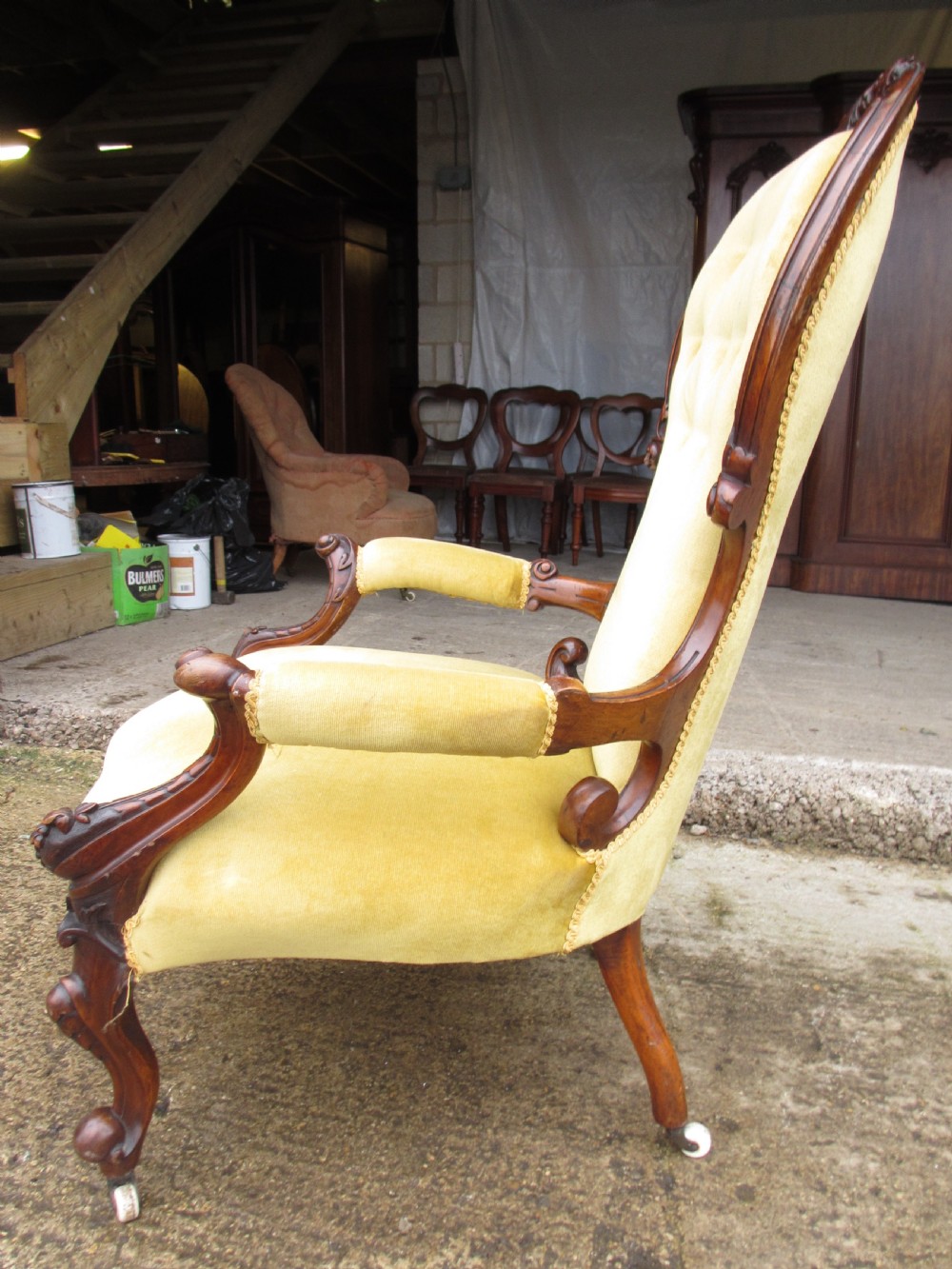 A Victorian walnut open armchair featuring a curved spoon back with button-tufted yellow velvet upholstery and carved cabriole legs. View XII