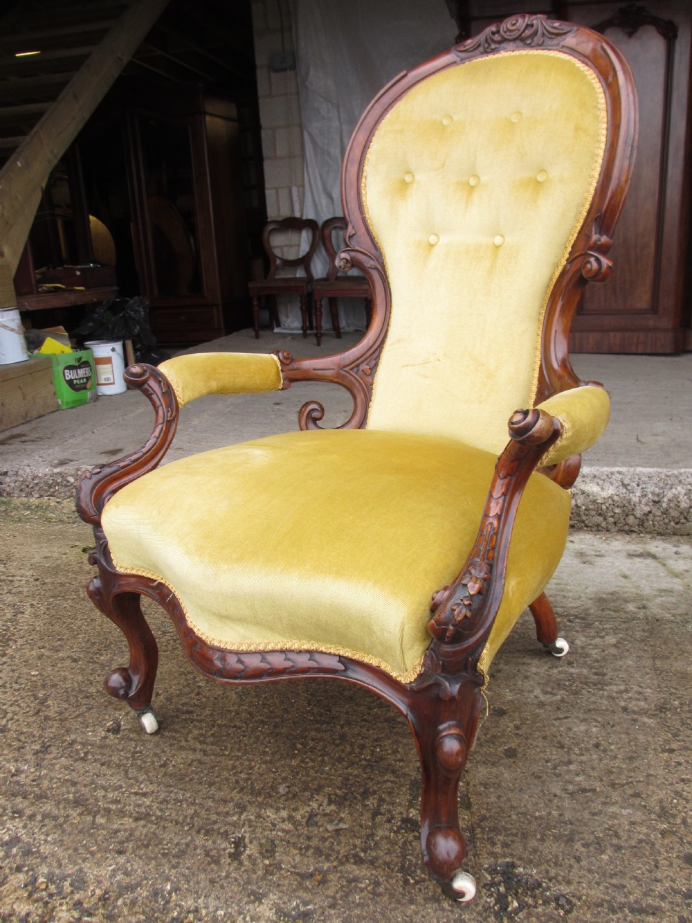 A Victorian walnut open armchair featuring a curved spoon back with button-tufted yellow velvet upholstery and carved cabriole legs. View XIV